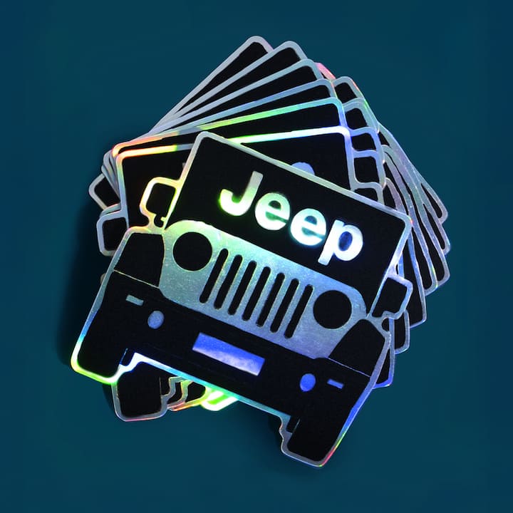Stack of holographic Jeep stickers on a dark background